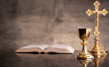 Katolik dini kavramı. Katolik sembolleri kompozisyonu. Haç, Monstrance, Kutsal İncil ve altın kadeh ahşap sunak ve gri arka plan. 