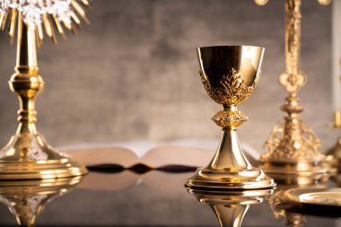 Katolik dini kavramı. Katolik sembolleri kompozisyonu. Haç, Monstrance, Kutsal İncil ve altın kadeh ahşap sunak ve gri arka plan. 
