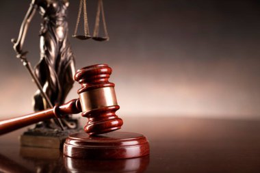 Hukuk ve adalet kavramı. Savaş suçları. Gavel, avukatlık bürosunda heykel ve terazi var. Kahverengi arkaplan.