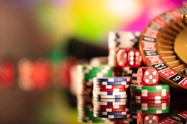Kumarhane teması. Kumar oyunları. Renkli bir arka planda rulet ve poker fişleri.