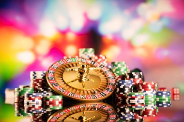 Kumarhane teması. Kumar oyunları. Renkli bir arka planda rulet ve poker fişleri.