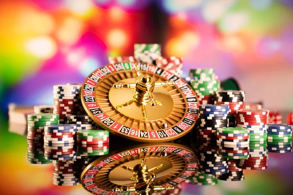 Kumarhane teması. Kumar oyunları. Renkli bir arka planda rulet ve poker fişleri.