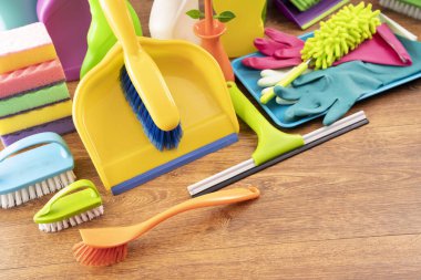 Spring house cleaning. Colorful cleaning kit on white wall background.