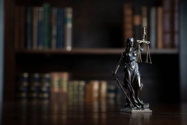 Judge office. Themis statue on the judge desk. Book shelf in the background.