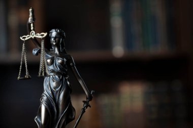 Yargıç ofisi. Yargıç masasındaki heykel. Arkaplanda kitap rafı.