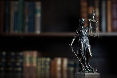 Judge office. Themis statue on the judge desk. Book shelf in the background.