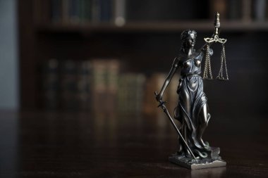 Yargıç ofisi. Yargıç masasındaki heykel. Arkaplanda kitap rafı.