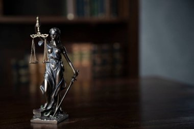 Judge office. Themis statue on the judge desk. Book shelf in the background.