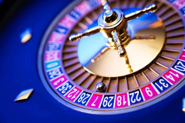 Kumarhane teması. Kumar oyunları. Mavi arka planda rulet ve poker fişleri.