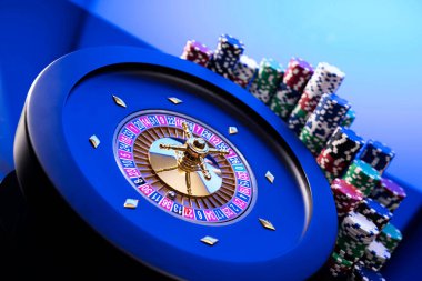 Kumarhane teması. Kumar oyunları. Mavi arka planda rulet ve poker fişleri.