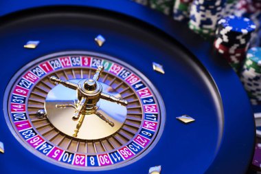 Kumarhane teması. Kumar oyunları. Mavi arka planda rulet ve poker fişleri.