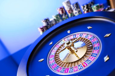 Kumarhane teması. Kumar oyunları. Mavi arka planda rulet ve poker fişleri.
