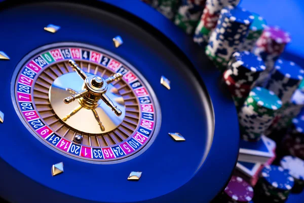 Kumarhane teması. Kumar oyunları. Mavi arka planda rulet ve poker fişleri.