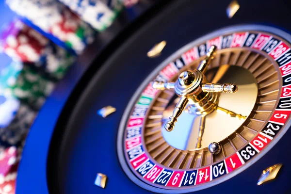 Kumarhane teması. Kumar oyunları. Mavi arka planda rulet ve poker fişleri.