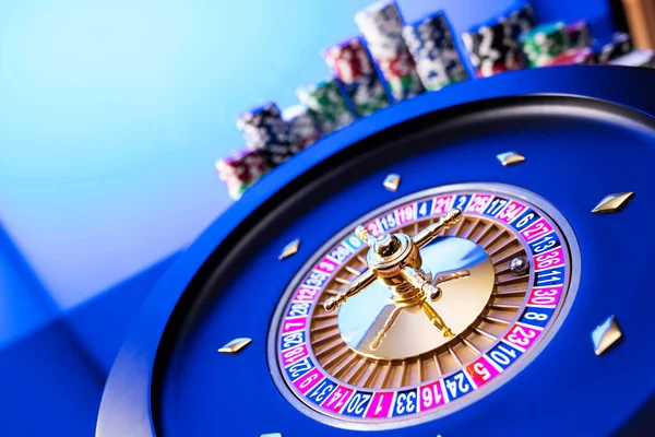 Kumarhane teması. Kumar oyunları. Mavi arka planda rulet ve poker fişleri.