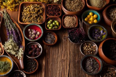 Doğal tıp geçmişi. Kâselerde çeşitli kuru otlar ve rustik ahşap masa üzerinde pirinç havan..