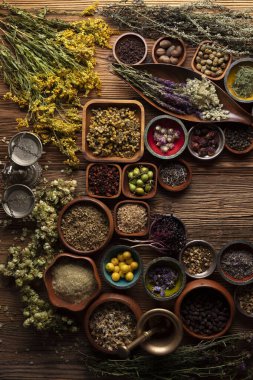 Doğal tıp geçmişi. Kâselerde çeşitli kuru otlar ve rustik ahşap masa üzerinde pirinç havan..