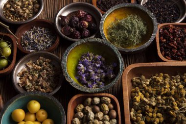 Doğal tıp geçmişi. Kâselerde çeşitli kuru otlar ve rustik ahşap masa üzerinde pirinç havan..