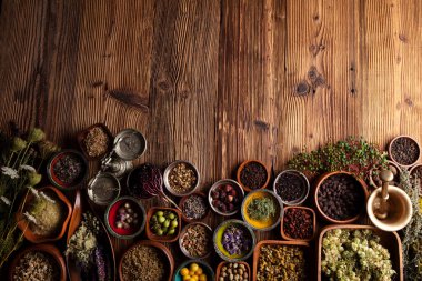 Doğal tıp geçmişi. Kâselerde çeşitli kuru otlar ve rustik ahşap masa üzerinde pirinç havan..