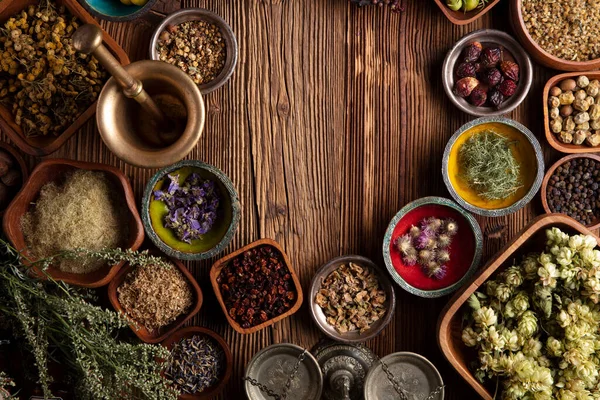 Doğal tıp geçmişi. Kâselerde çeşitli kuru otlar ve rustik ahşap masa üzerinde pirinç havan..