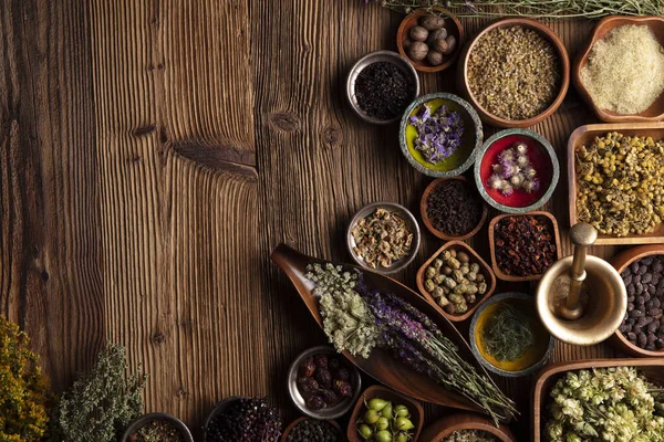 Doğal tıp geçmişi. Kâselerde çeşitli kuru otlar ve rustik ahşap masa üzerinde pirinç havan..