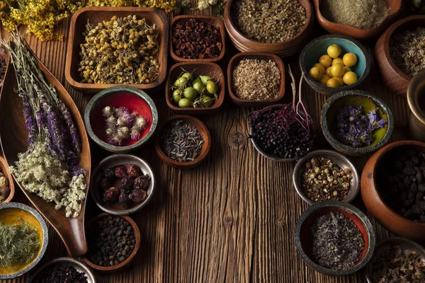 Doğal tıp geçmişi. Kâselerde çeşitli kuru otlar ve rustik ahşap masa üzerinde pirinç havan..