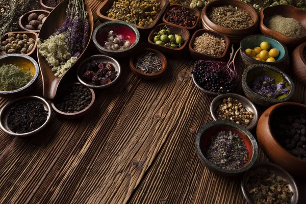Doğal tıp geçmişi. Kâselerde çeşitli kuru otlar ve rustik ahşap masa üzerinde pirinç havan..