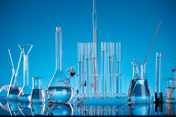Covid 'e karşı test ve ilaç ile ilgili laboratuvar araştırmaları. Mikroskop, shethoscope, cam tüpler ve mavi arka planda deney tüpleri..