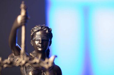 Avukatlık bürosu. Kanun sembolleri: Heykel ve ölçek. Mavi ışık arkaplanı.