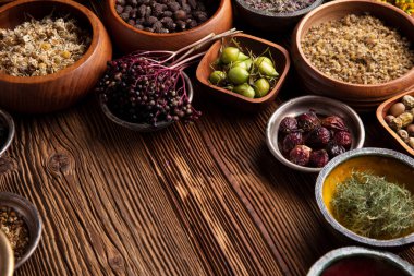  Doğal tıp geçmişi. Kâselerde çeşitli kuru otlar ve rustik ahşap masa üzerinde pirinç havan..