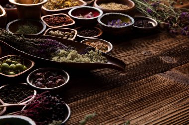  Doğal tıp geçmişi. Kâselerde çeşitli kuru otlar ve rustik ahşap masa üzerinde pirinç havan..