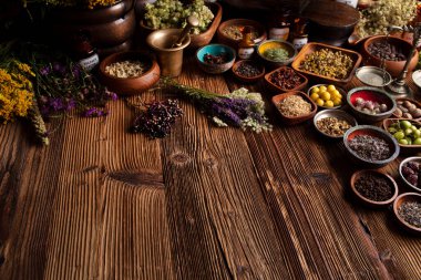 Doğal tıp geçmişi. Kâselerde çeşitli kuru otlar ve rustik ahşap masa üzerinde pirinç havan..
