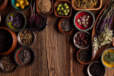  Doğal tıp geçmişi. Kâselerde çeşitli kuru otlar ve rustik ahşap masa üzerinde pirinç havan..