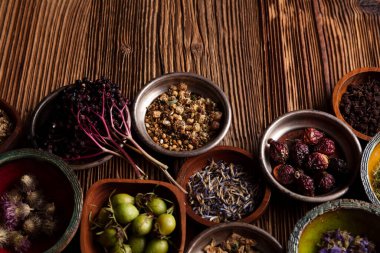  Doğal tıp geçmişi. Kâselerde çeşitli kuru otlar ve rustik ahşap masa üzerinde pirinç havan..