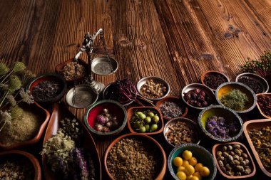  Doğal tıp geçmişi. Kâselerde çeşitli kuru otlar ve rustik ahşap masa üzerinde pirinç havan..