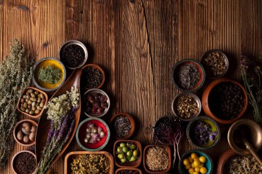  Doğal tıp geçmişi. Kâselerde çeşitli kuru otlar ve rustik ahşap masa üzerinde pirinç havan..