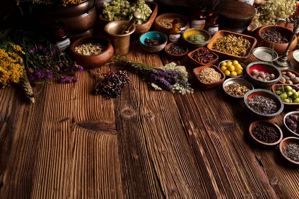  Doğal tıp geçmişi. Kâselerde çeşitli kuru otlar ve rustik ahşap masa üzerinde pirinç havan..