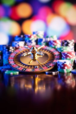 Kumarhane teması. Renkli arkaplanda rulet çarkı ve poker çipleri.