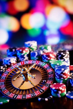 Kumarhane teması. Renkli arkaplanda rulet çarkı ve poker çipleri.