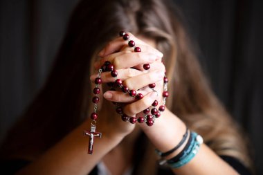 Christianity theme  prayer.  Christian woman with Bible praying with hands crossed keeping rosary. clipart