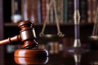 Yargıç ofisi. Gavel ve tartıyı yargıç masasına koy. Arkaplanda kitap rafı.