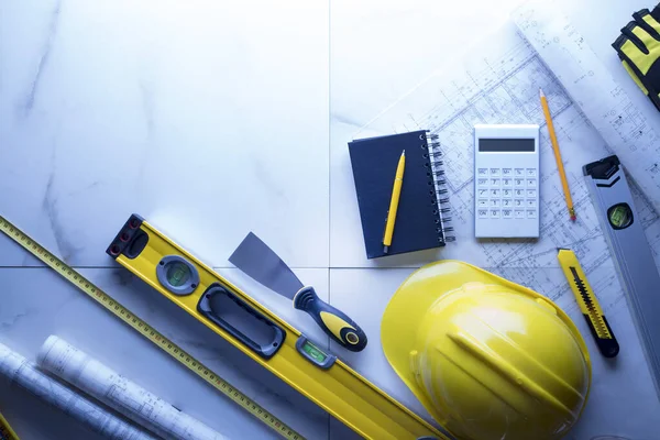 Contractor theme. Plans,  notebook and tool kit of the contractor: yellow hardhat, libella and yardstick.
