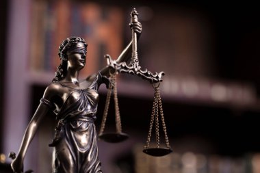 Law theme - judge office. Themis and gavel  on the judge desk. Book shelf  in the background.