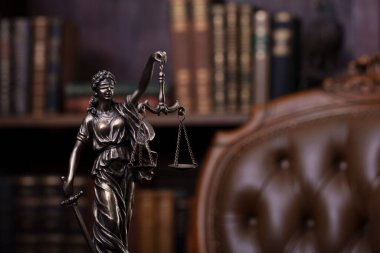 Law theme - judge office. Themis and gavel  on the judge desk. Book shelf  in the background.