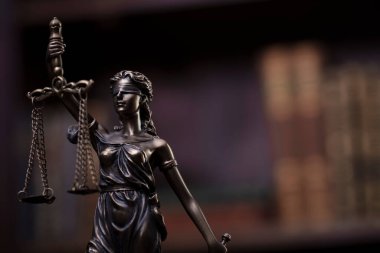 Law theme - judge office. Themis and gavel  on the judge desk. Book shelf  in the background.