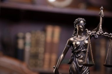 Law theme - judge office. Themis and gavel  on the judge desk. Book shelf  in the background.