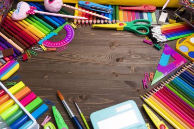 School supplies. Set of colorful school accessories isolated on the brown wooden background. Top view.