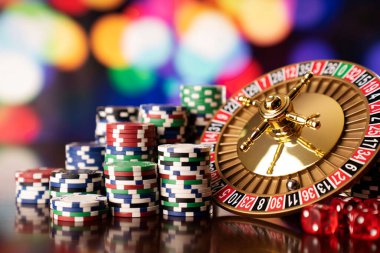 Casino. Roulette wheel, dice and poker chips on the colorful bokeh background.