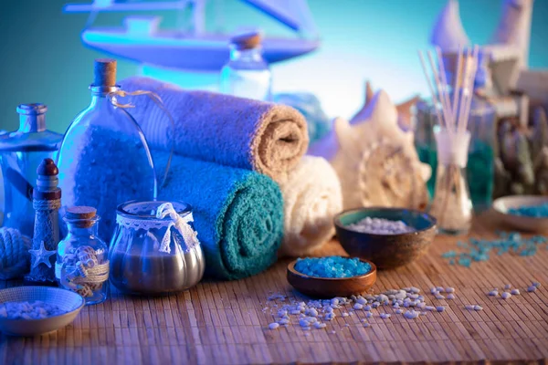 Spa and wellness concept. Bottles with bath and spa cosmetics, rolled up towels, bath salts and care products on wooden rustic paneling.