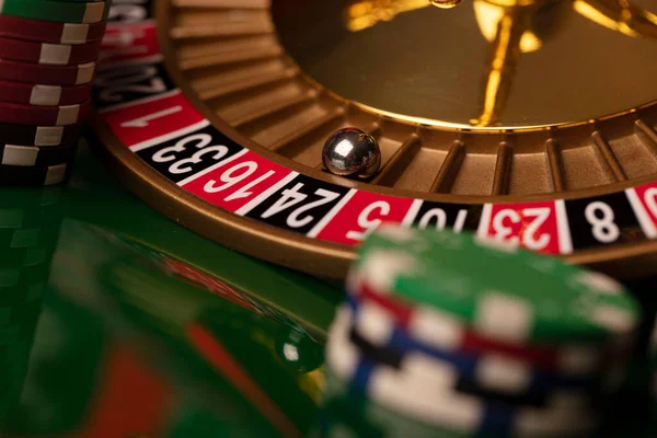卡西诺绿色闪光背景上的轮盘赌和扑克筹码 — 图库照片